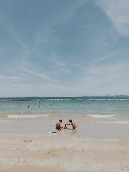 2名坐在海滩岸边的女人 · 免费素材图片