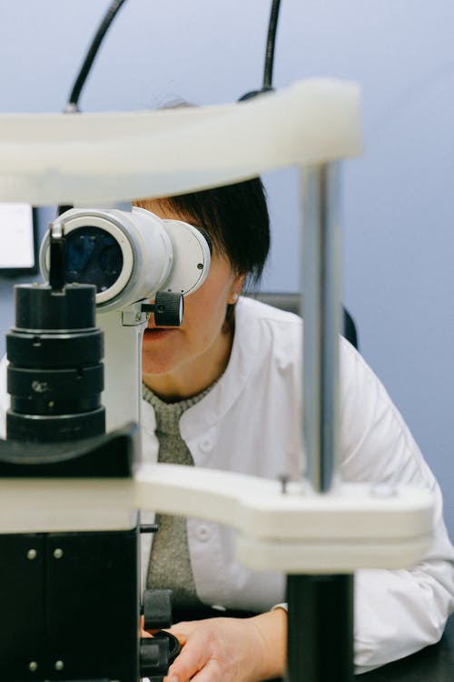 不可识别的女科学家，通过显微镜观看 · 免费素材图片