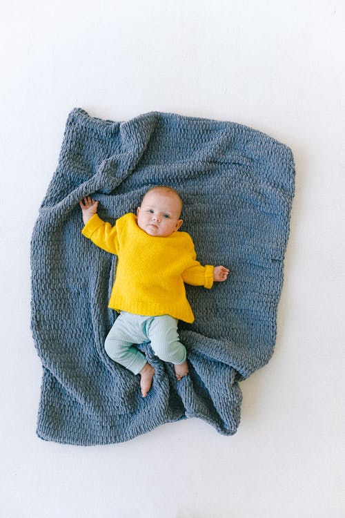 可爱的刚出生的婴儿，躺在工作室的软蓝色格子 · 免费素材图片