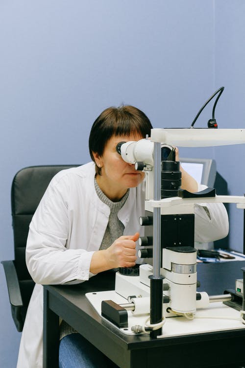 通过裂隙灯显微镜看的匿名女科学家 · 免费素材图片