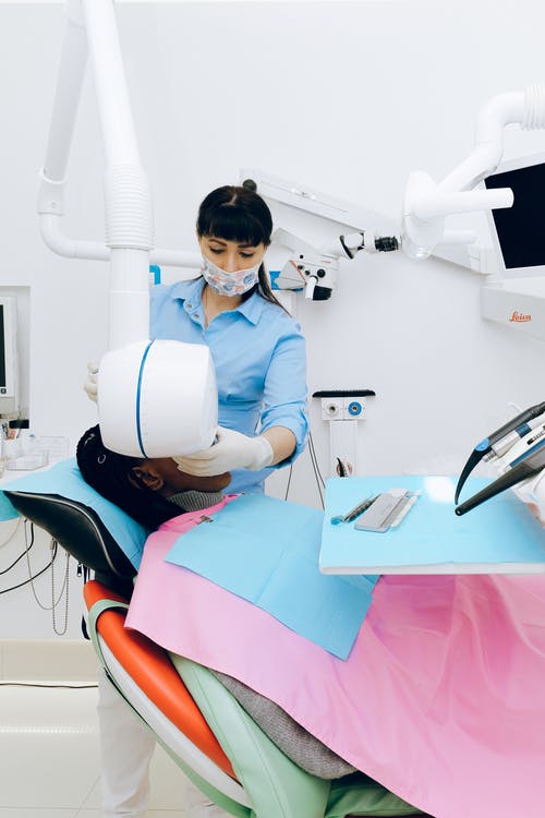 在与病人的现代办公室工作的女牙医 · 免费素材图片