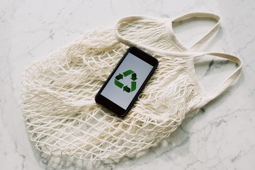 带绿色回收标志和网袋的手机 · 免费素材图片