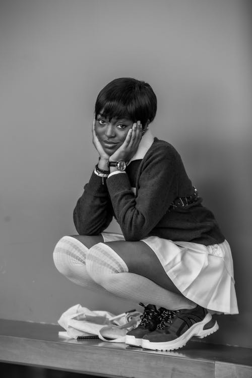 蹲在墙上的时尚沉思黑女人 · 免费素材图片