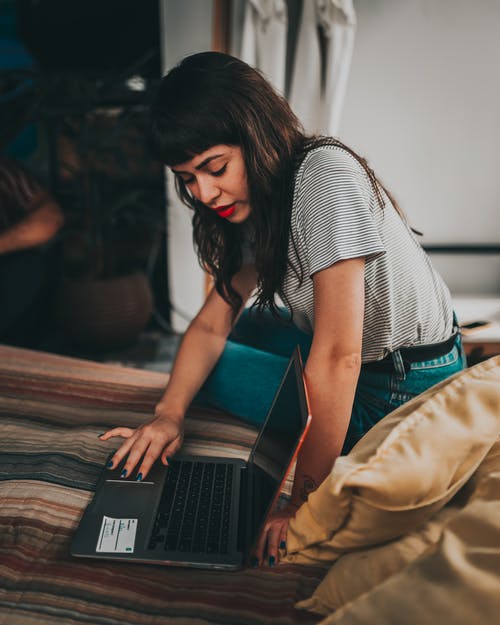 女人在垫子上使用笔记本电脑和展示屏幕 · 免费素材图片