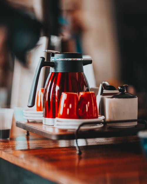 红色陶瓷杯和水壶在咖啡厅的木制柜台上 · 免费素材图片
