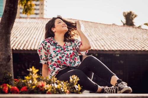 女人坐在花顶和黑色的裤子 · 免费素材图片