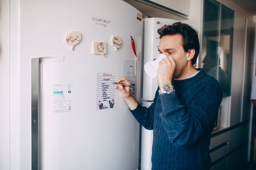 年轻人在冰箱上的文字提醒和在家喝咖啡 · 免费素材图片