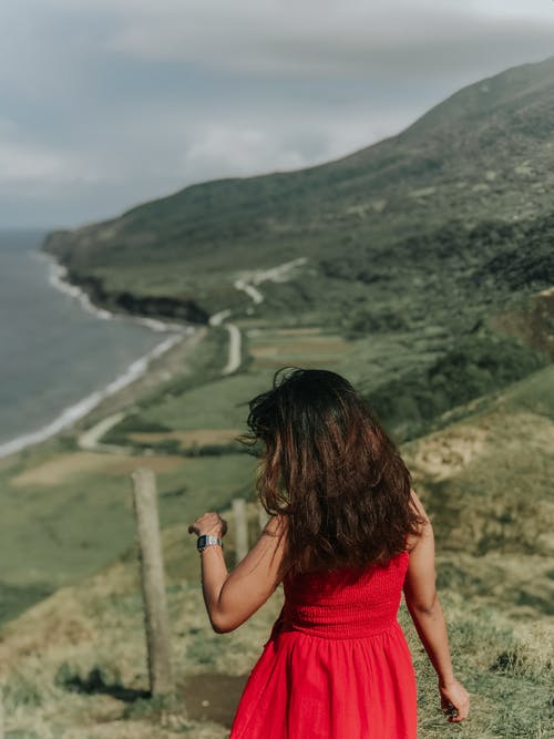 红色背心的女人拍张绿山的照片 · 免费素材图片