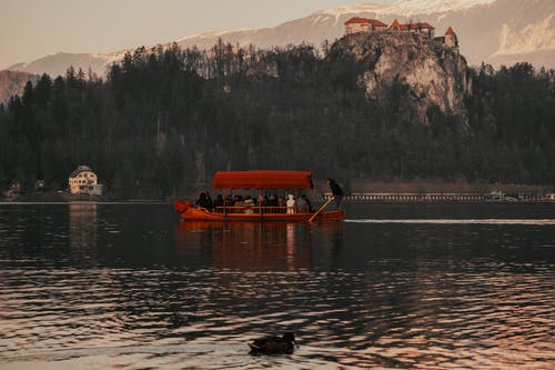 人们骑着小船在山附近的湖上 · 免费素材图片