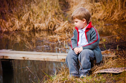 蓝色牛仔牛仔裤，坐在棕色木码头上的男孩 · 免费素材图片