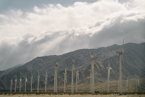 多云的天空下山附近的风力涡轮机 · 免费素材图片