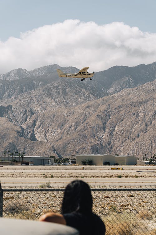 匿名的女人看着飞行直升机在山脊和多云的天空下 · 免费素材图片