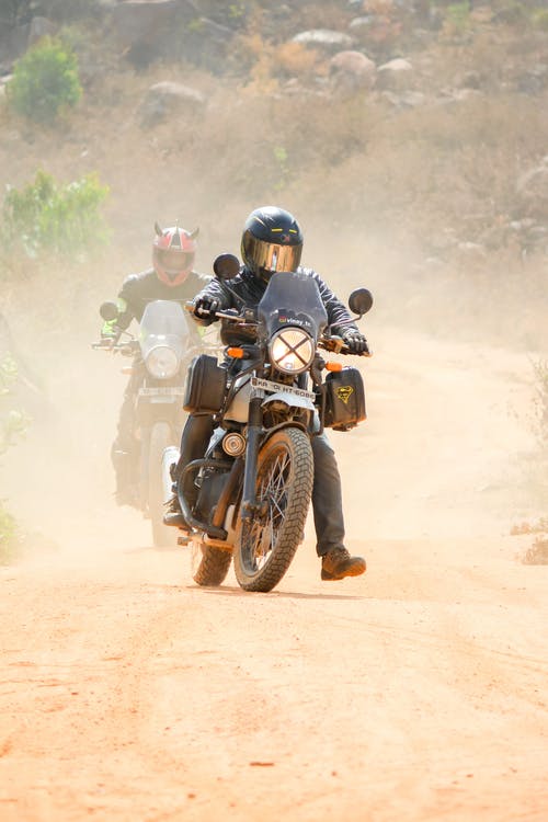 男子骑摩托车在土路上 · 免费素材图片