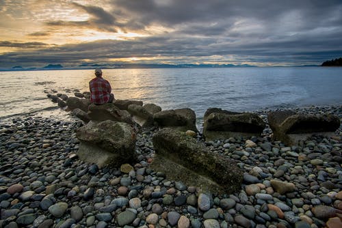 男子坐在一块大石头上 · 免费素材图片
