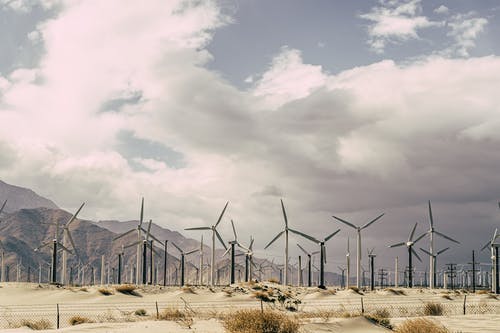 风力涡轮机在白多云的天空下的沙子上 · 免费素材图片