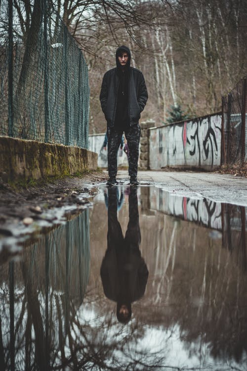 黑夹克和黑裤子站在水坑附近的人 · 免费素材图片