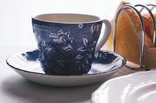 白色和蓝色花卉陶瓷茶杯在碟上 · 免费素材图片