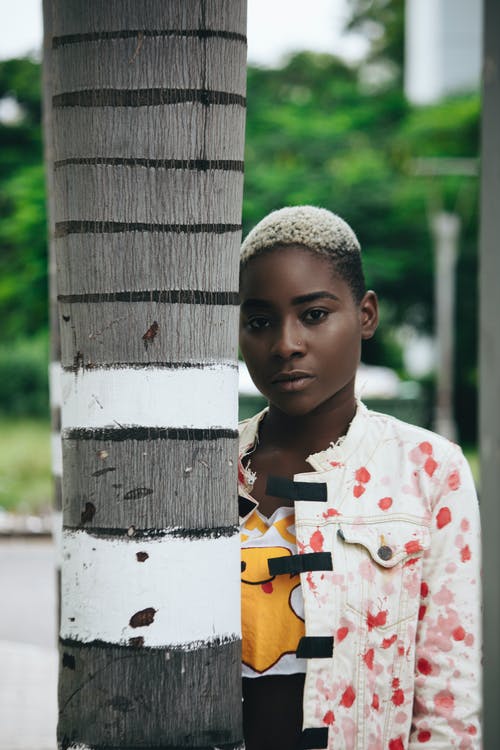 白色和红色的花卉纽扣衬衫站在白色的木栅栏旁边的男孩 · 免费素材图片