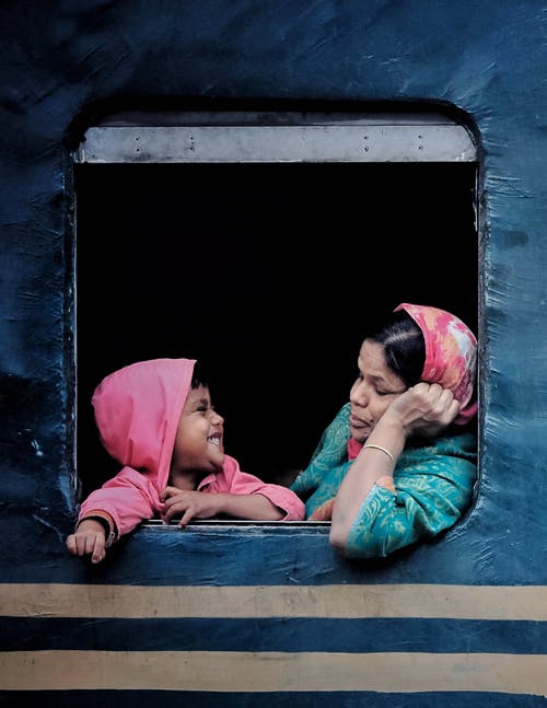 女人穿着粉红色的头巾和一个孩子在火车里面 · 免费素材图片