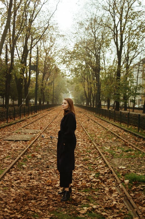 黑色外套站在火车铁轨上的女人 · 免费素材图片