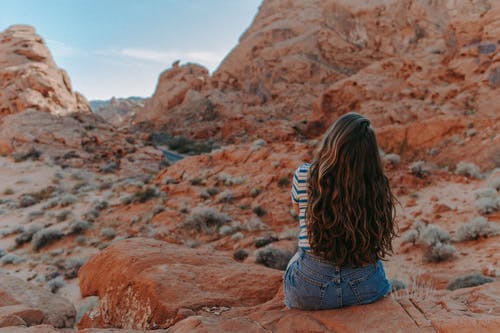 蓝色牛仔短裤的女人坐在布朗岩山 · 免费素材图片