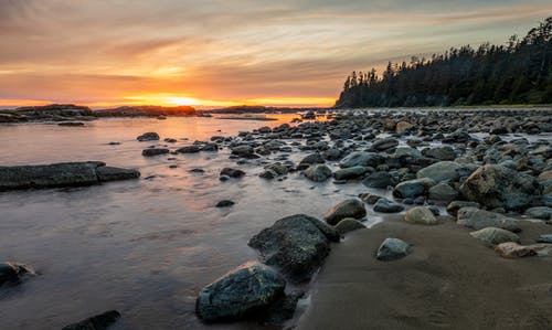 岩石海岸与日落期间在岸上的岩石 · 免费素材图片