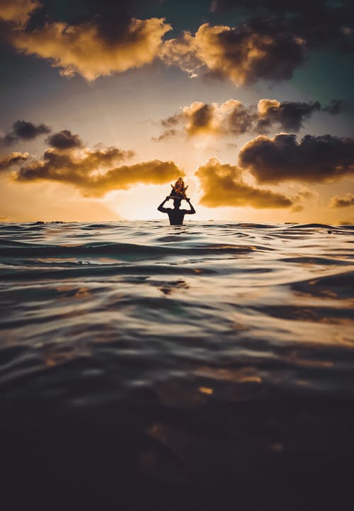 人在日落时在水中的剪影 · 免费素材图片