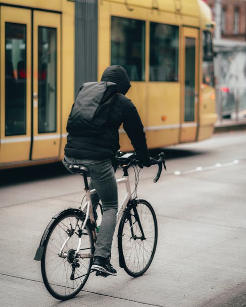 穿黑夹克的人骑自行车 · 免费素材图片