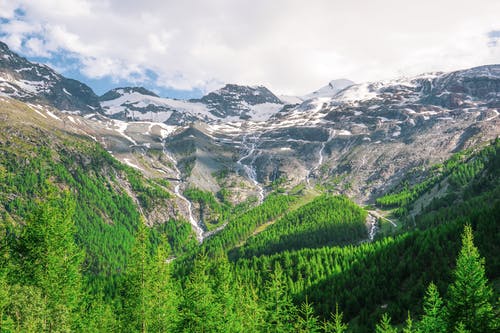 绿树和白雪覆盖的天空下的白雪覆盖的山脉 · 免费素材图片