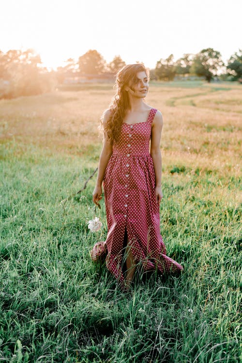 红色和白色的圆点裙的女人站在绿草地上 · 免费素材图片
