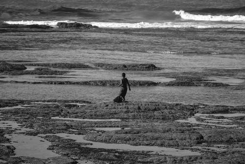 在海滩上行走的人的灰度照片 · 免费素材图片