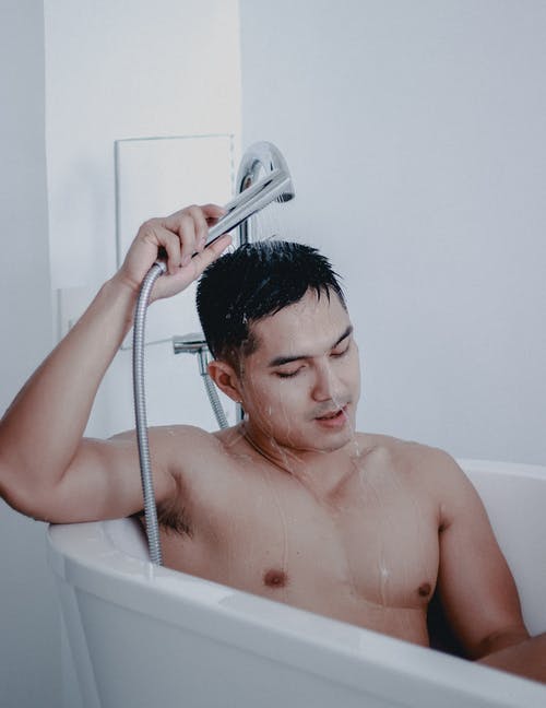 在浴缸里拿着淋浴的裸照人 · 免费素材图片