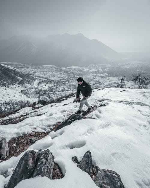 黑夹克的人在雪上行走 · 免费素材图片