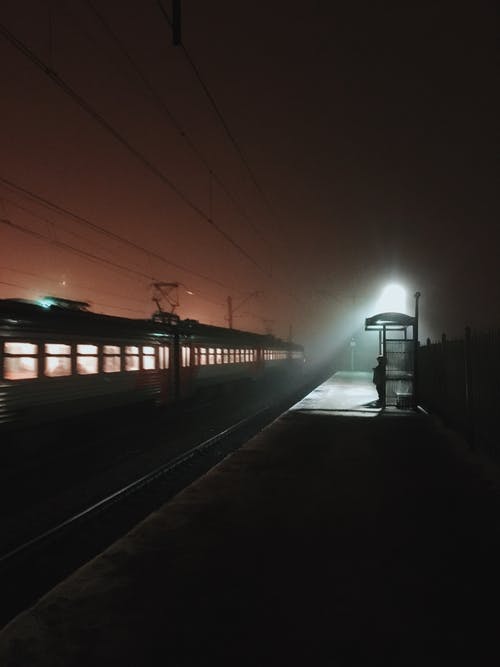 夜间站在火车平台上的人的身影 · 免费素材图片