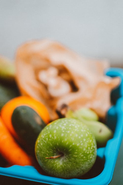 青苹果水果上蓝色的塑料容器 · 免费素材图片