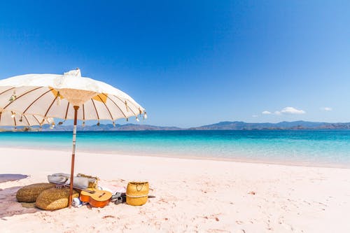 海滩上的白色和棕色伞 · 免费素材图片