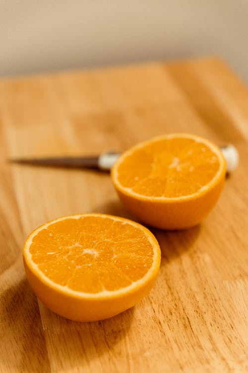在棕色木菜板上切橙色水果 · 免费素材图片