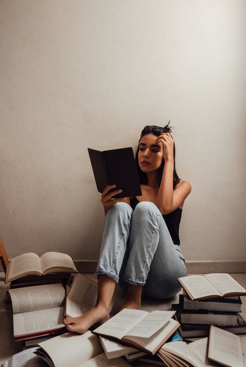 黑色背心和牛仔牛仔裤读一本书的女人 · 免费素材图片