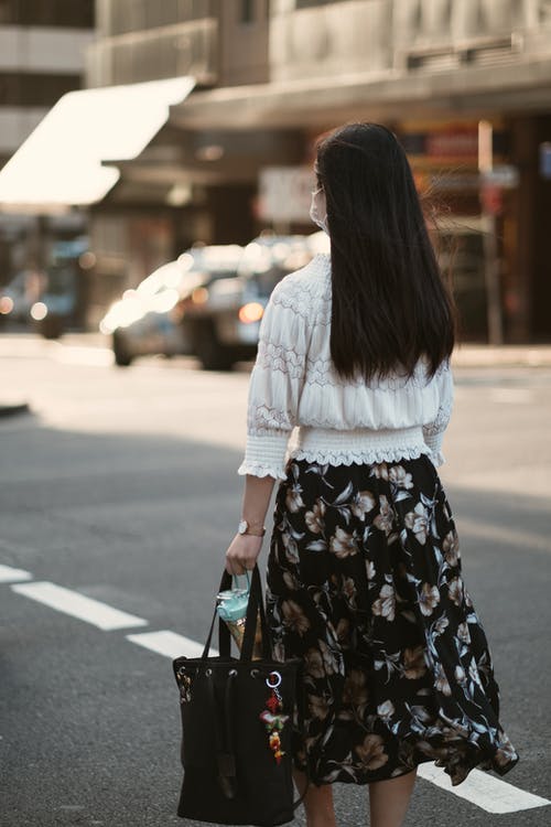 白色长袖衬衫和黑色的花裙，站在人行道上的女人 · 免费素材图片