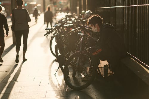穿黑夹克的男人在自行车前 · 免费素材图片