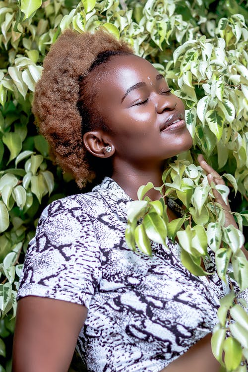 微笑的非洲裔美国老妇，闭着眼睛，在绿色的植物中放松 · 免费素材图片