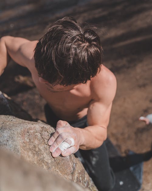 肌肉发达的年轻运动员，在晴朗的一天爬上悬崖的墙上 · 免费素材图片