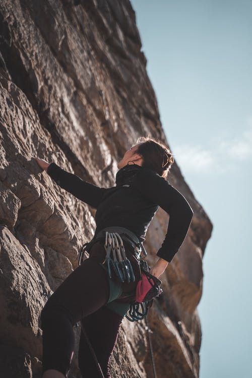 嬉戏的女登山者，在阳光灿烂的日子在石质悬崖上上升 · 免费素材图片