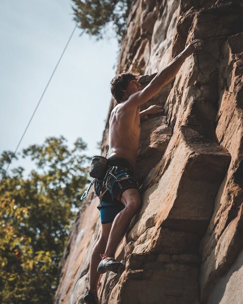勇敢的赤膊登山攀登在岩石上，在阳光灿烂的日子 · 免费素材图片