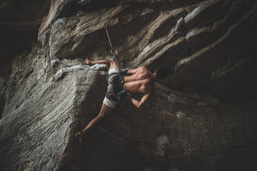 强壮的男性登山者挂在山沟的绳索上 · 免费素材图片