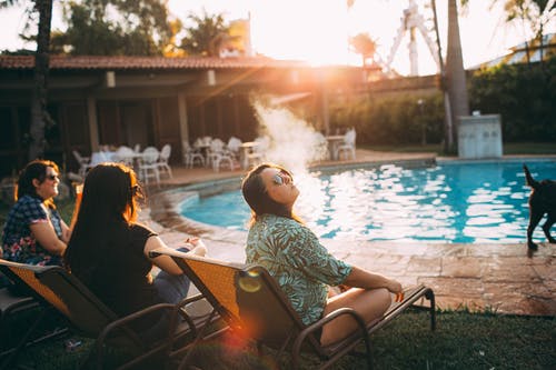 年轻女子在游泳池边休息时抽烟 · 免费素材图片
