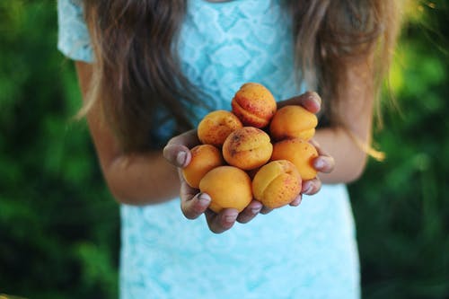 女孩抱着黄色的圆形水果 · 免费素材图片