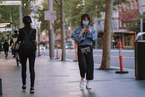牛仔夹克和黑色的裤子，在人行道上行走的女人 · 免费素材图片