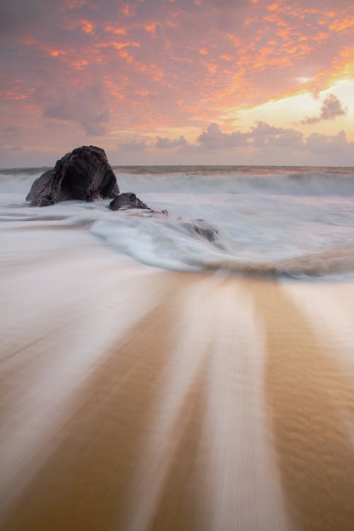 海浪在日落时在岸上崩溃 · 免费素材图片