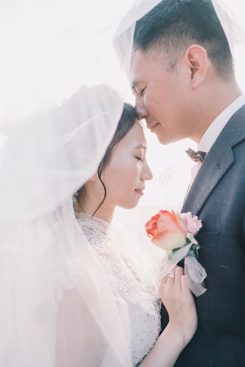 浪漫新婚亚洲夫妇站在一起，双眼紧闭在面纱下 · 免费素材图片